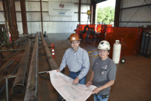 San Jacinto College graduate Jim Hodges, left, looks over construction project plans with Archie Devault, shop superintendent for Total Industrial Services. Photo credit: Rob Vanya
