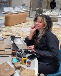 San Jacinto College fine arts alumna Jeri Rae Venegas painting at a table