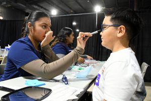 Eye care technology student measuring elementary student for new frames