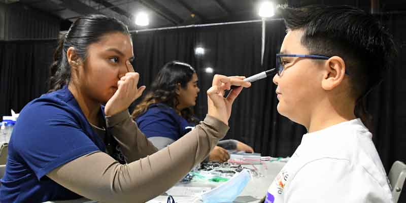 Eye care technology student measuring elementary student for new frames