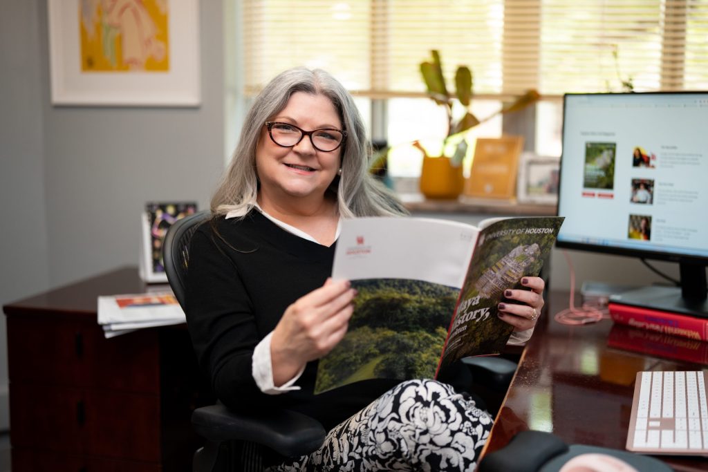 Carrie Taylor seated at her office desk holding a magazine
