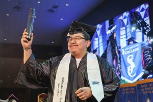 Student holding diploma high at spring 2026 graduation