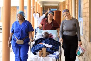 San Jacinto College nursing graduates pushing a surgery patient on a gurney