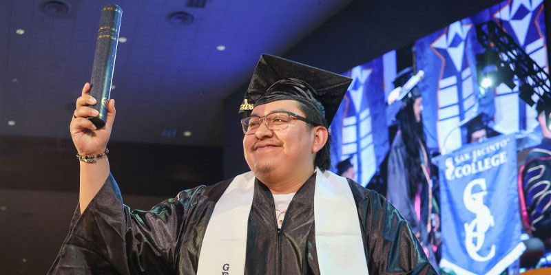 Student holding diploma high at spring 2026 graduation